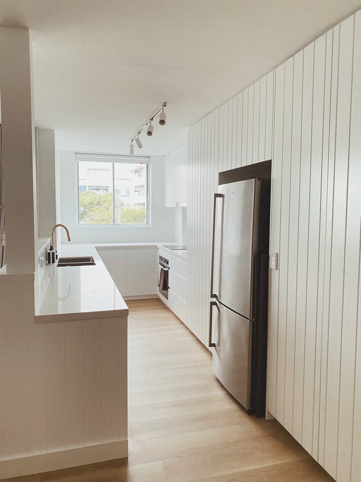 Galley kitchen with white cabinetry, VJ panelling and integrated fridge, Penkivil St Bondi