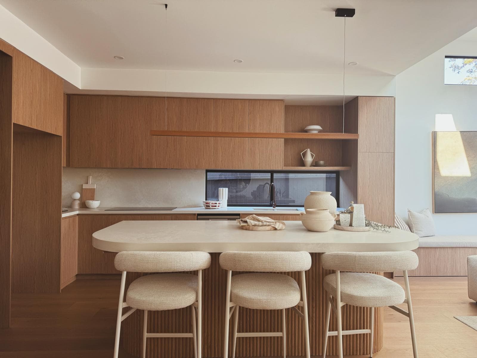 Open-plan kitchen with timber cabinetry, fluted island bench and upholstered bar stools, 64 Botany St