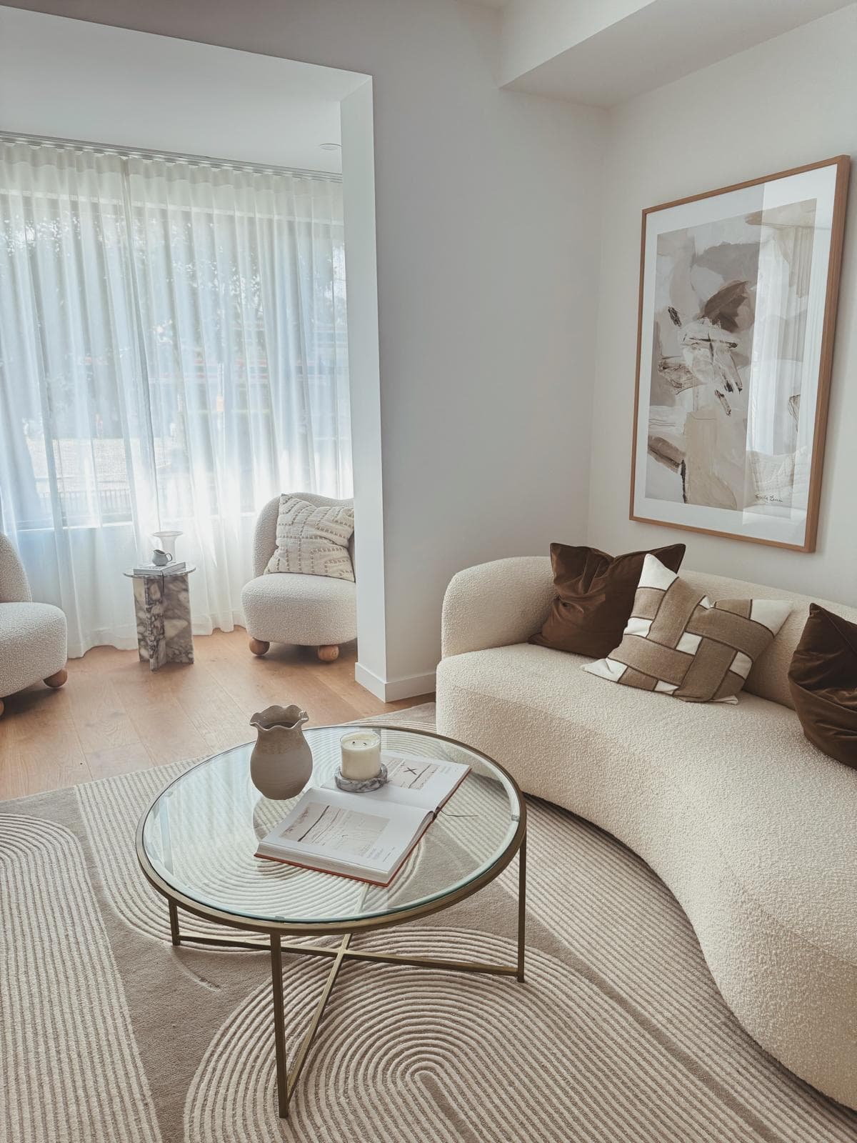 Living room with curved boucle sofa, glass coffee table and framed artwork, 64 Botany St