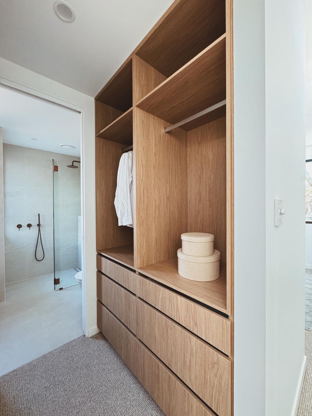 Walk-in wardrobe with timber joinery, open shelving and ensuite beyond, 64 Botany St