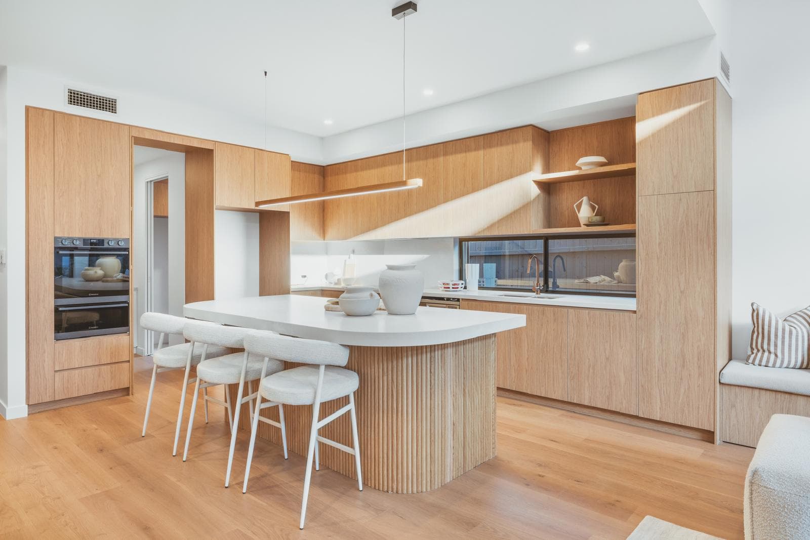 Kitchen island with white stone benchtop, pendant lighting and timber cabinetry, 64 Botany St