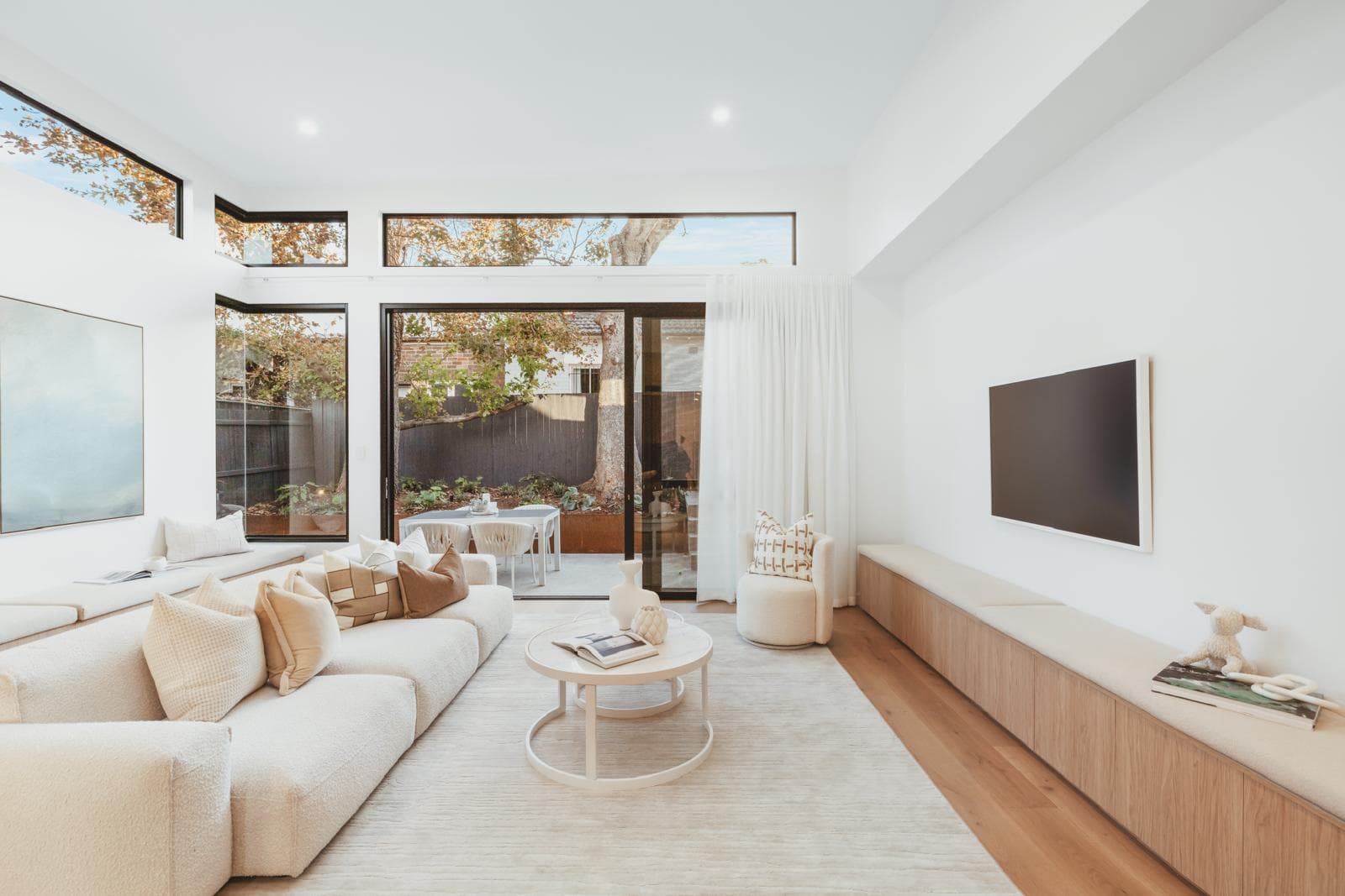 Living room with wall-mounted TV, built-in bench seating and sliding doors to the garden, 64 Botany St