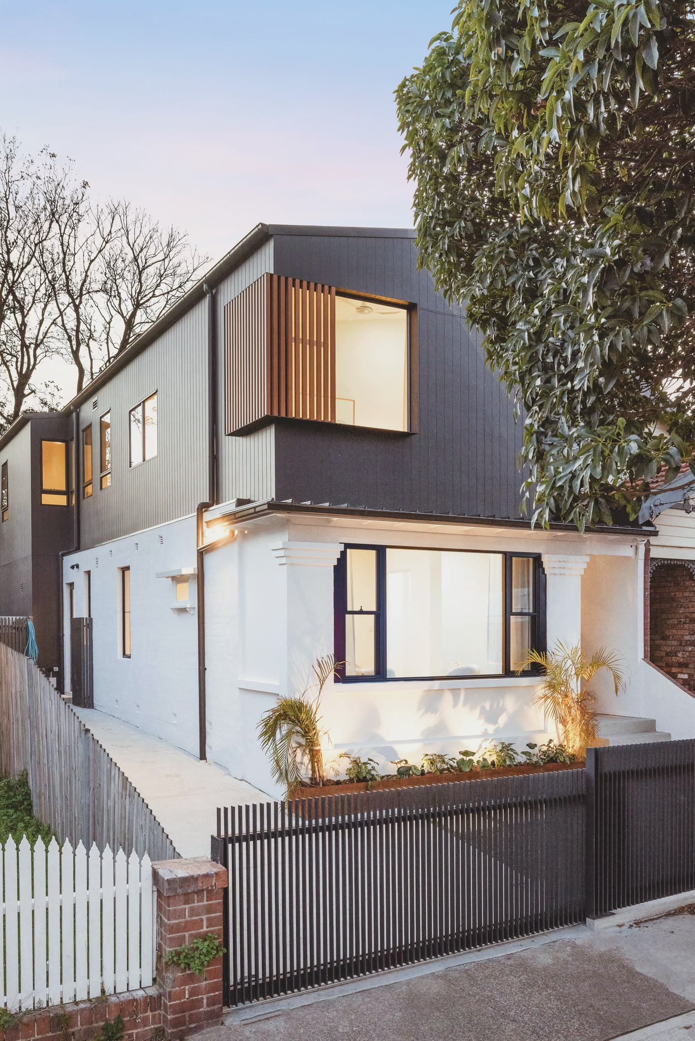 Dusk exterior, 64 Botany St second storey addition, charcoal cladding over original white weatherboard, Kingsford