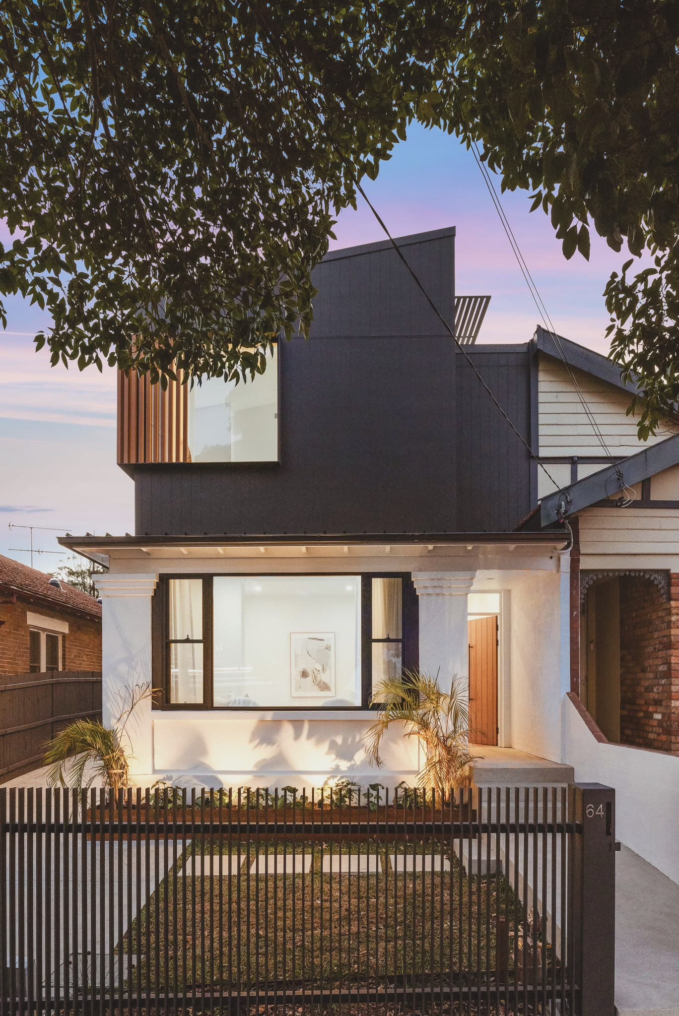 Federation cottage with charcoal-clad second storey addition at dusk